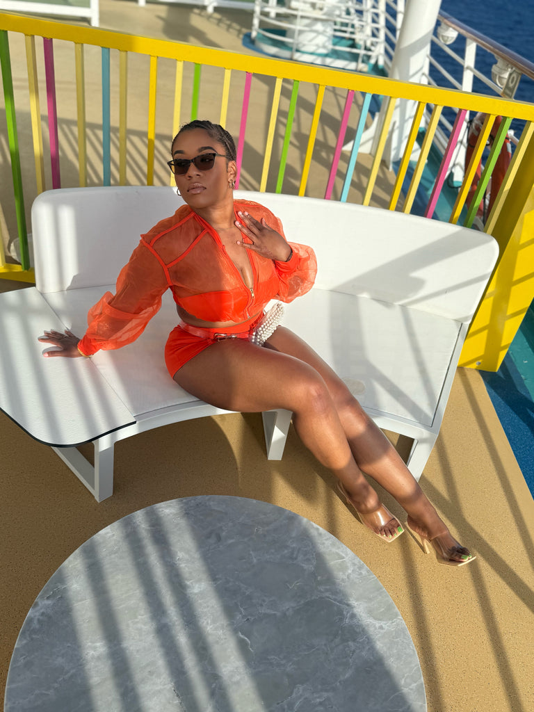 Woman in an orange outfit sitting on a white chair with colorful railing in the background